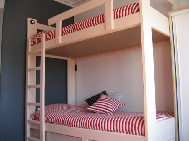 Une chambre avec 2 lits superposés, un clic-clac et une penderie.